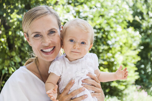 Portrait of happy mother holding her baby girl outdoors - TCF05888