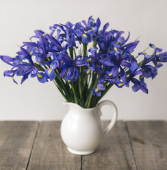 Nahaufnahme von lila Blumen in einer Vase auf einem Holztisch an der Wand - CAVF49663