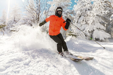 Junger Mann beim Skifahren auf Schnee gegen Bäume im Winter in voller Länge - CAVF49693