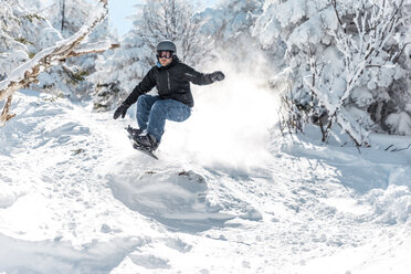 Mann in voller Länge beim Snowboarden auf Schnee gegen Bäume im Winter - CAVF49696