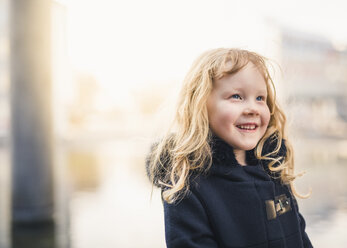 Smiling girl looking away while wearing coat outdoors - CAVF49701