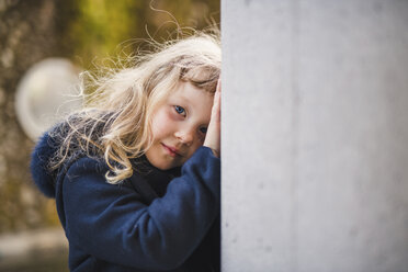 Portrait of girl wearing coat by wall - CAVF49702