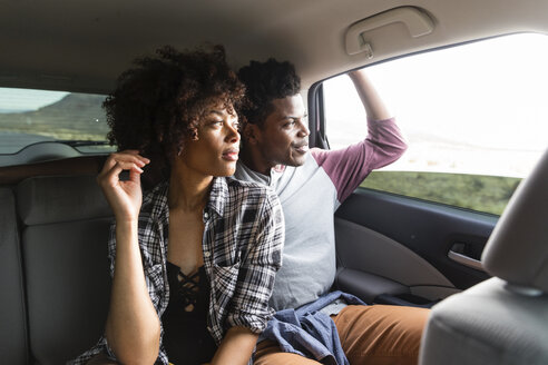 Paar schaut durch das Fenster, während es im Auto unterwegs ist - CAVF49727