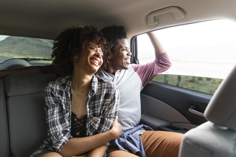 Glückliches Paar, das durch das Fenster schaut, während es im Auto unterwegs ist, lizenzfreies Stockfoto