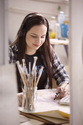 Woman listening music while painting at home - CAVF49742