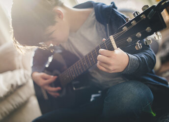 Boy playing guitar at home - CAVF49757