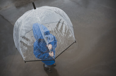 Hohe Winkelansicht des Jungen mit Regenschirm auf der Straße während der Regenzeit stehen - CAVF49761