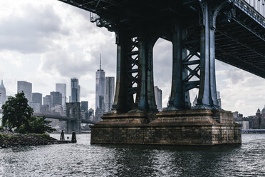 Manhattan Bridge over East River in city against cloudy sky - CAVF49788