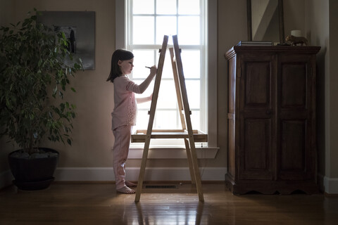 Seitenansicht eines Mädchens, das zu Hause auf einer Leinwand malt, lizenzfreies Stockfoto