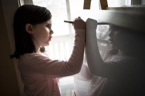 Side view of cute girl drawing on artist's canvas at home - CAVF49790