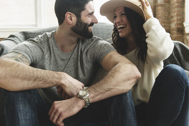 Happy couple sitting by bed at home - CAVF49834