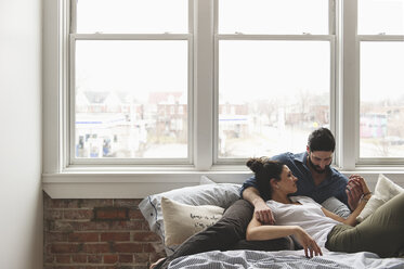 Romantisches Paar entspannt sich auf dem Bett am Fenster zu Hause - CAVF49841