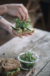 Cropped hands of woman making sandwich on wooden table at home - CAVF49853