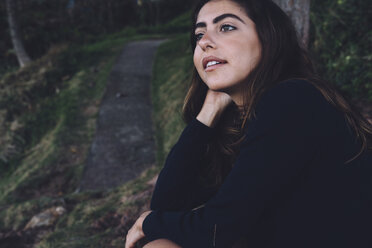 Side view of woman looking away while sitting in forest - CAVF49911