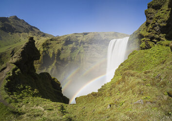 Blick auf den Regenbogen über dem Wasserfall Skogafoss bei klarem Himmel - CAVF49942