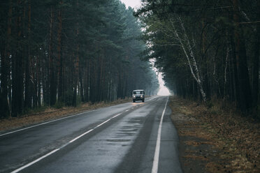 Van driving on country road through pine forest - VPIF00921