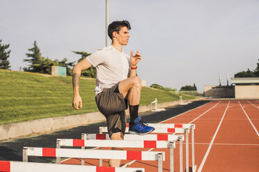 Athlete doing warm-up exercises on a tartan track for a hurdle race - ACPF00351