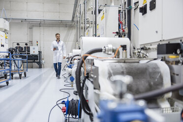 Employee checking manufacturing machines in high tech company, using digital tablet - DIGF05218