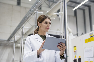 Woman checking manufacturing machines in high tech company, using digital tablet - DIGF05222