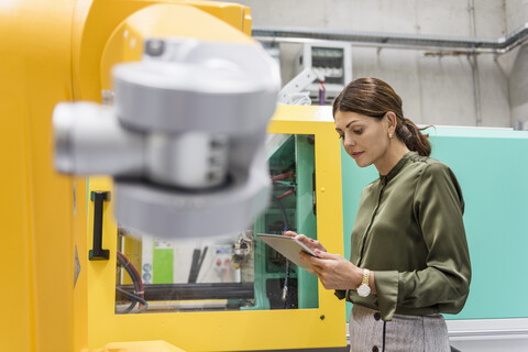 Geschäftsfrau prüft Industrieroboter in Hightech-Unternehmen, lizenzfreies Stockfoto