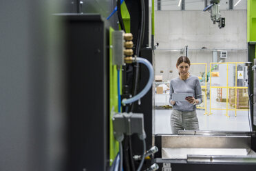 Businesswoman in high tech company controlling manufacturing machines, using digital tablet - DIGF05241