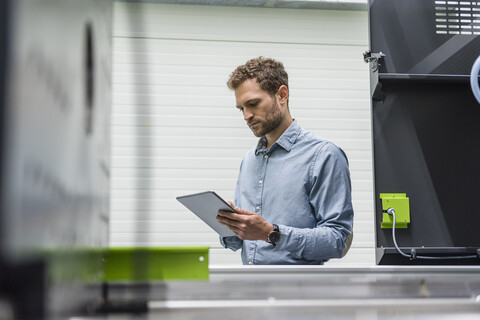 Businessman in high tech company controlling manufacturing machines, using digital tablet stock photo