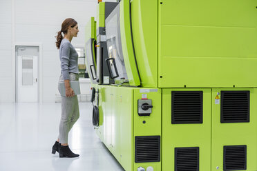 Geschäftsfrau in einem Hightech-Unternehmen, das Produktionsmaschinen kontrolliert - DIGF05251