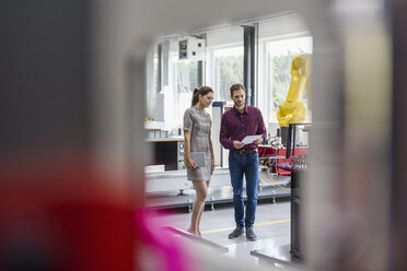 Geschäftsmann und Frau bei einer Besprechung vor Industrierobotern in einem Hightech-Unternehmen - DIGF05261