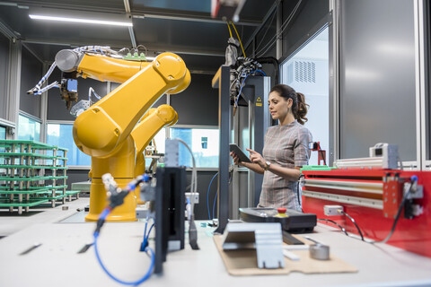 Businesswoman checking industrial robot in high tech company stock photo