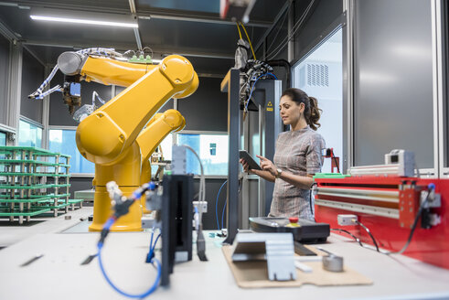 Businesswoman checking industrial robot in high tech company - DIGF05262