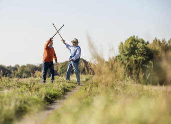 Zwei alte Freunde fechten auf den Feldern mit ihren Wanderstöcken - UUF15470