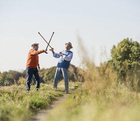 Zwei alte Freunde fechten auf den Feldern mit ihren Wanderstöcken - UUF15471