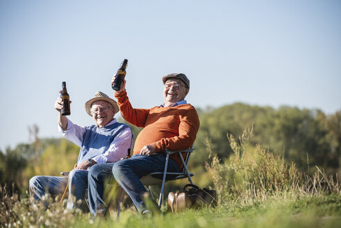 Two old friends sitting in the fields, drinking beer, talking about old times - UUF15481