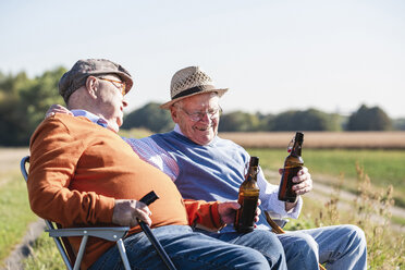 Zwei alte Freunde sitzen auf der Wiese, trinken Bier und reden über alte Zeiten - UUF15483