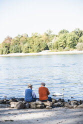 Two old friends sitting by the river side, watching swans - UUF15501