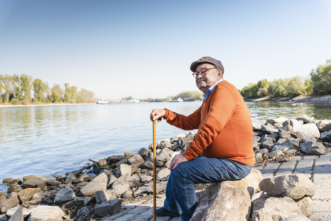 Alter Mann sitzt am Fluss, lizenzfreies Stockfoto