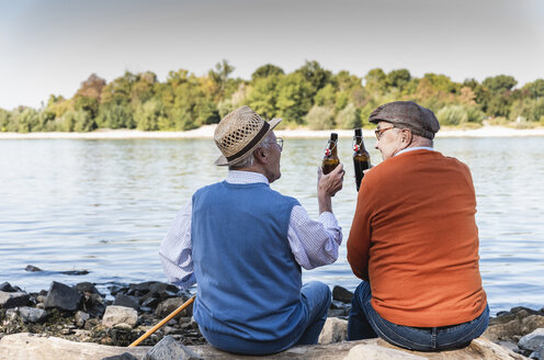 Old friends sitting by the riverside, drinking beer - UUF15518