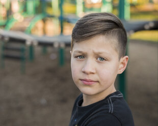 Porträt eines traurigen Jungen auf dem Spielplatz - CAVF49968