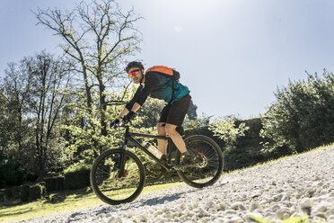 Full length of young man riding mountain bike at park during sunny day - CAVF49985