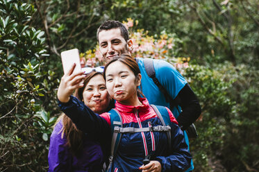 Glückliche Freunde, die ein Selfie machen, während sie im Wald stehen - CAVF49989