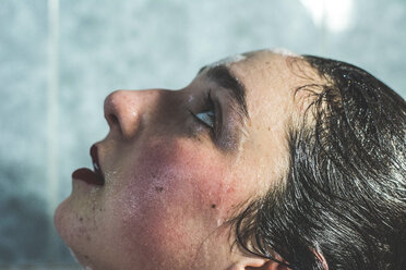 Nahaufnahme einer nassen jungen Frau mit Make-up, die beim Baden im heimischen Badezimmer nach oben schaut - CAVF49991