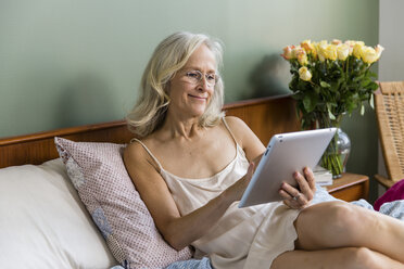 Ältere Frau benutzt Tablet-Computer auf dem Bett zu Hause - CAVF50050