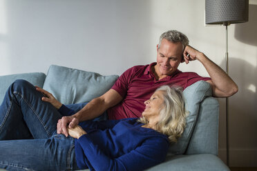 Loving couple relaxing while lying on sofa at home - CAVF50066