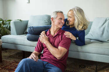 Happy couple talking while resting in living room at home - CAVF50068