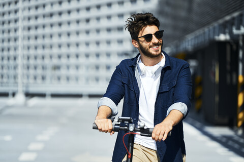 Portrait of smiling man with electric scooter outdoors stock photo