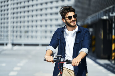 Portrait of smiling man with electric scooter outdoors - BSZF00760