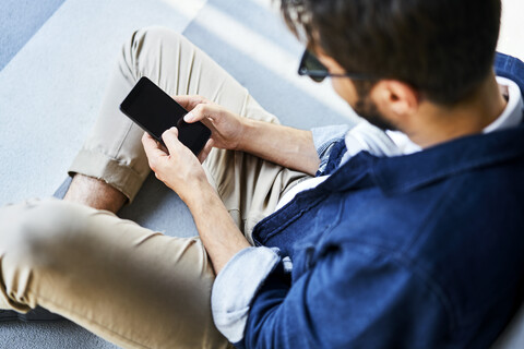 Young man sitting on the ground text messaging stock photo