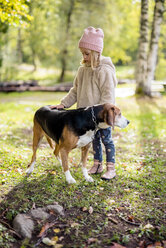 Little girl stroking dog in autumnal garden - PSIF00123