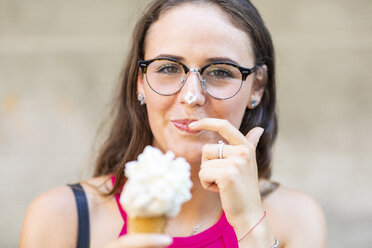 Porträt einer lächelnden jungen Frau, die Eiscreme isst - WPEF00932