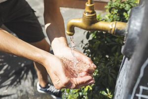 Nahaufnahme von Händen und Wasser, das aus einem öffentlichen Brunnen fließt - WPEF00934